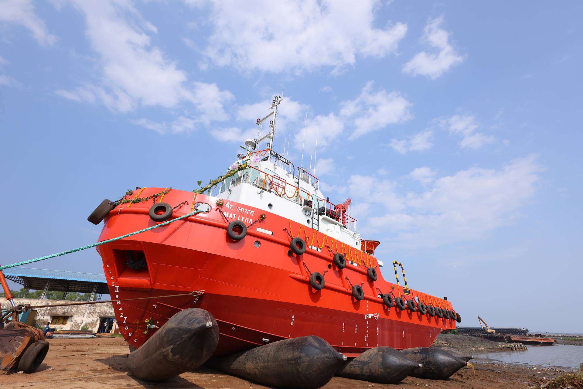 The bow of a red tug resting on airbags at the yard